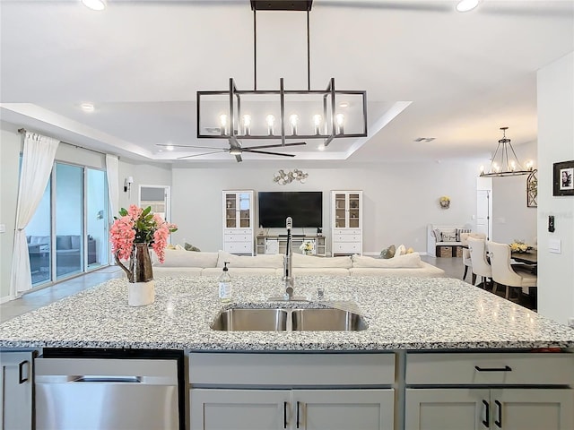 kitchen with a raised ceiling, sink, and a center island with sink