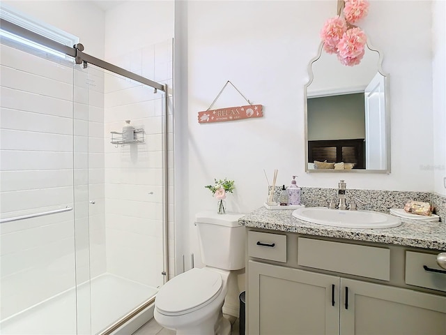 bathroom featuring vanity, toilet, and a shower with shower door