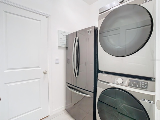 laundry area with light tile patterned floors and stacked washer and clothes dryer