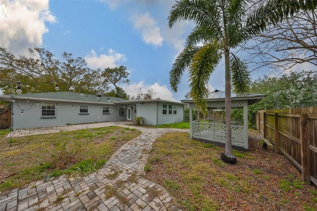 rear view of property featuring a gazebo, a yard, and a patio