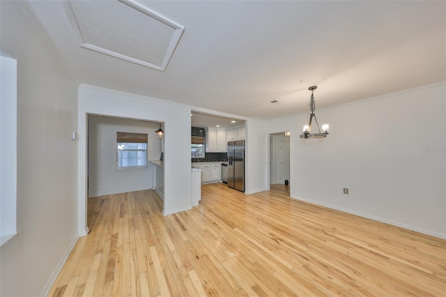 unfurnished living room featuring a chandelier, light hardwood / wood-style flooring, and ornamental molding