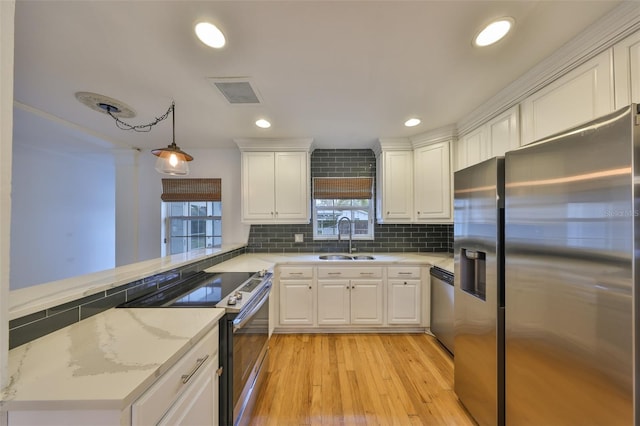 kitchen with sink, white cabinets, hanging light fixtures, and stainless steel appliances