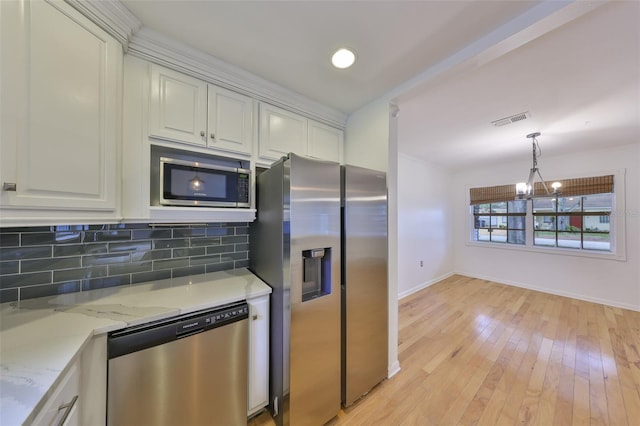 kitchen with white cabinets, tasteful backsplash, light stone countertops, and stainless steel appliances