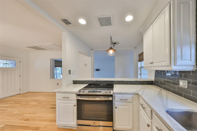 kitchen featuring kitchen peninsula, hanging light fixtures, stainless steel electric range oven, white cabinetry, and a healthy amount of sunlight