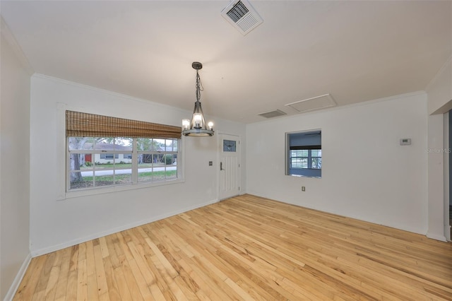 empty room with light wood-type flooring, a chandelier, and ornamental molding