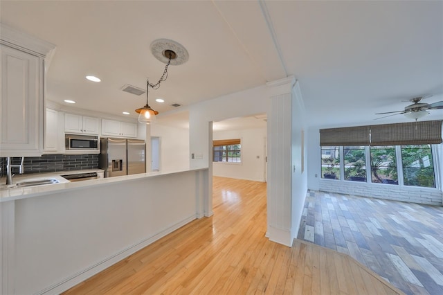 kitchen featuring tasteful backsplash, white cabinetry, sink, pendant lighting, and stainless steel appliances