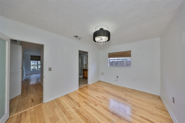 empty room with hardwood / wood-style flooring, a textured ceiling, and an inviting chandelier