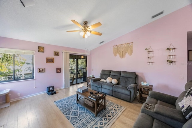 living room with ceiling fan, a textured ceiling, vaulted ceiling, and light wood-type flooring