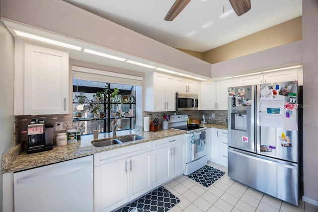 kitchen featuring appliances with stainless steel finishes, decorative backsplash, white cabinets, light stone counters, and sink