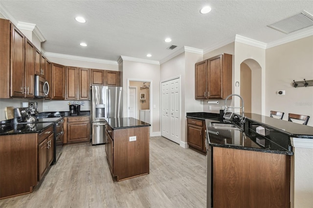 kitchen featuring a kitchen island, appliances with stainless steel finishes, separate washer and dryer, dark stone counters, and kitchen peninsula