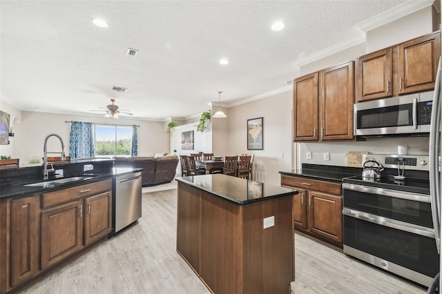 kitchen featuring a kitchen island, sink, light hardwood / wood-style floors, stainless steel appliances, and crown molding