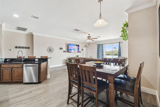 dining space featuring ceiling fan, ornamental molding, light hardwood / wood-style flooring, and a textured ceiling