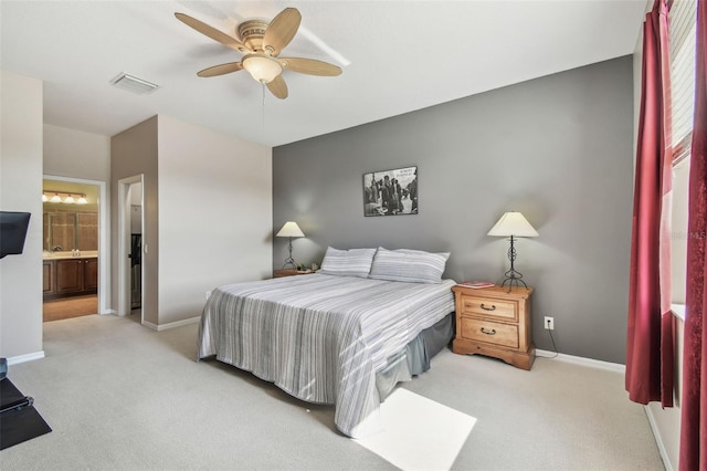 bedroom featuring ceiling fan, light colored carpet, and ensuite bathroom