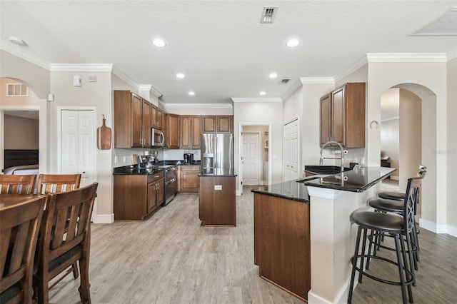 kitchen featuring a center island, light hardwood / wood-style flooring, a kitchen breakfast bar, kitchen peninsula, and stainless steel appliances