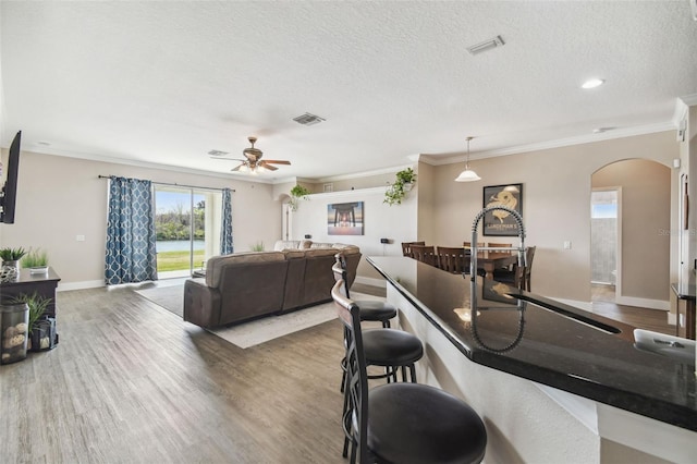 living room featuring ceiling fan, ornamental molding, dark hardwood / wood-style floors, and a textured ceiling