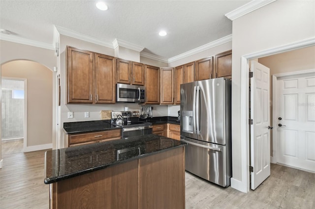 kitchen featuring appliances with stainless steel finishes, a center island, light hardwood / wood-style flooring, and dark stone counters