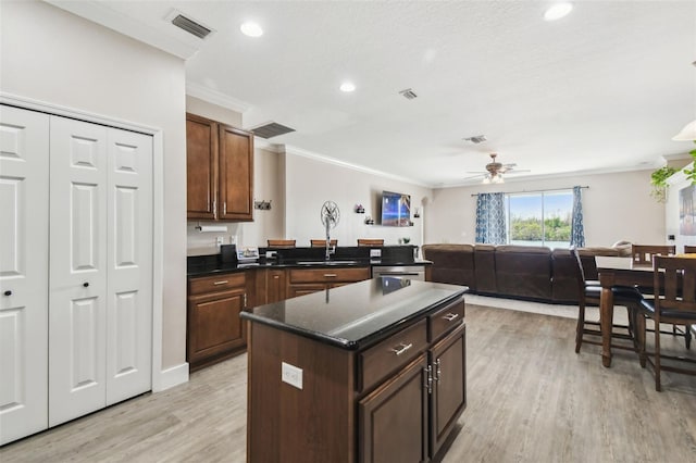 kitchen featuring a kitchen island, ornamental molding, ceiling fan, dark brown cabinets, and light hardwood / wood-style flooring