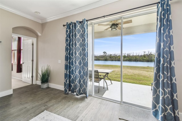 doorway with a water view, ceiling fan, wood-type flooring, and crown molding