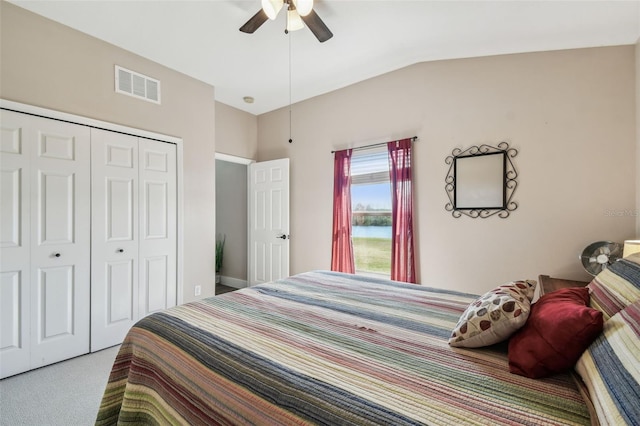 carpeted bedroom with ceiling fan, lofted ceiling, and a closet