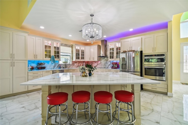 kitchen featuring appliances with stainless steel finishes, backsplash, decorative light fixtures, wall chimney exhaust hood, and a center island