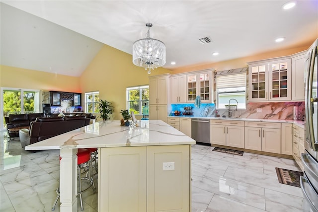 kitchen with backsplash, vaulted ceiling, pendant lighting, stainless steel dishwasher, and a center island