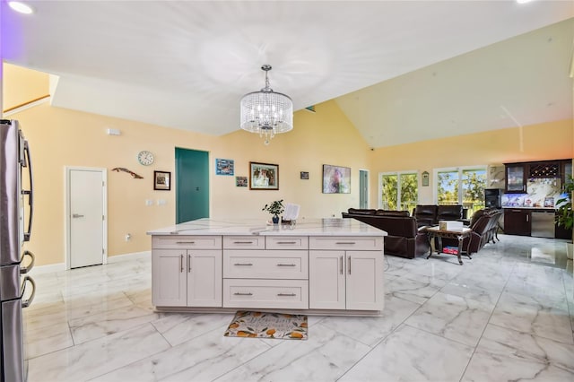 kitchen featuring white cabinetry, stainless steel appliances, hanging light fixtures, vaulted ceiling, and light stone counters