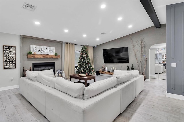 living room featuring vaulted ceiling with beams and a fireplace