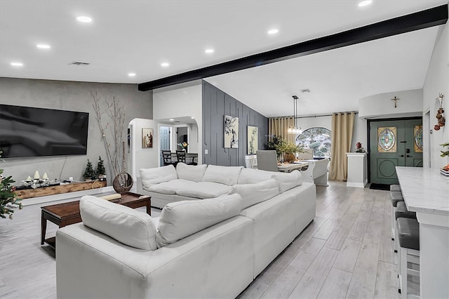 living room featuring light hardwood / wood-style flooring, an inviting chandelier, and vaulted ceiling with beams