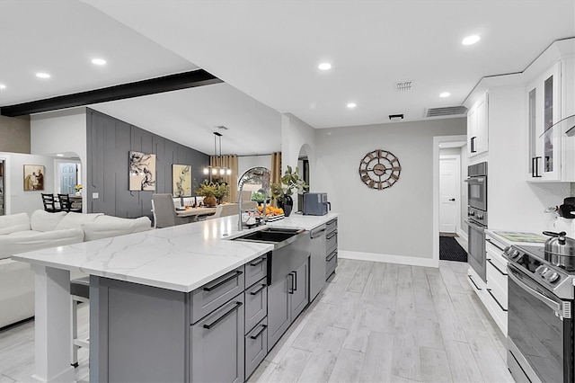 kitchen with stainless steel electric range oven, a breakfast bar area, a spacious island, white cabinets, and beamed ceiling