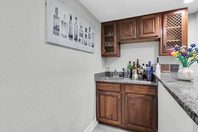 bar with dark brown cabinets and sink