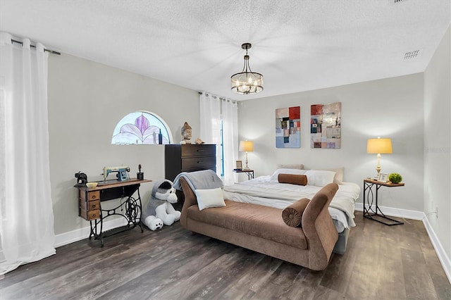 bedroom featuring dark hardwood / wood-style flooring, an inviting chandelier, and a textured ceiling