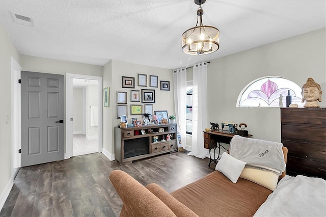 sitting room with a textured ceiling, an inviting chandelier, and dark hardwood / wood-style flooring