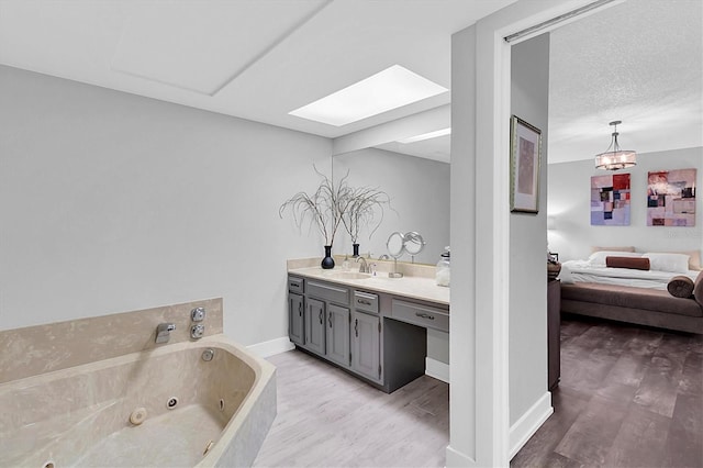 bathroom with a skylight, hardwood / wood-style flooring, a bathtub, a textured ceiling, and vanity