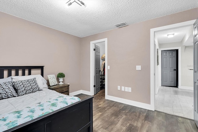 bedroom featuring a textured ceiling and dark hardwood / wood-style flooring