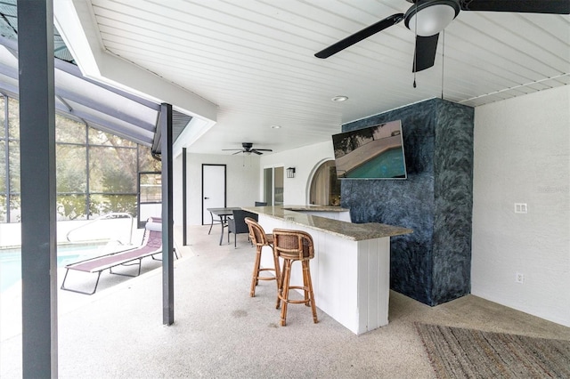 kitchen with ceiling fan, lofted ceiling, a kitchen bar, and kitchen peninsula