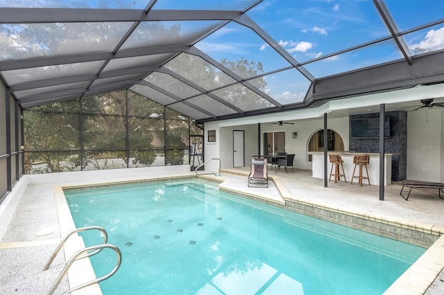 view of pool with ceiling fan, a lanai, exterior bar, and a patio area