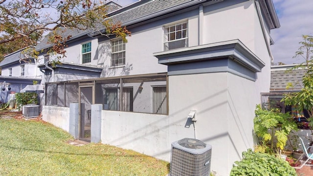 view of property exterior with central air condition unit, a yard, and a sunroom