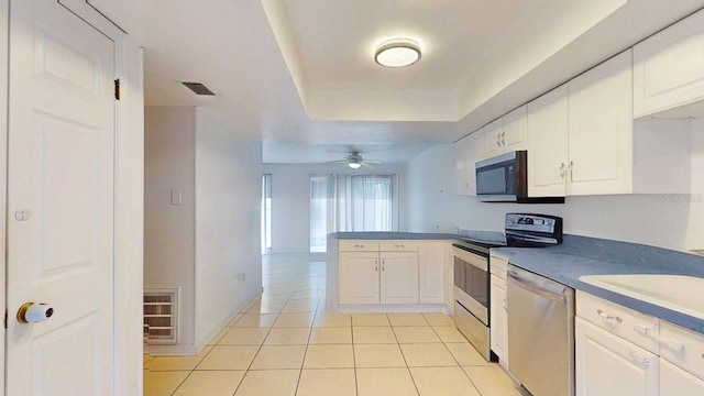 kitchen featuring light tile patterned floors, white cabinets, appliances with stainless steel finishes, and kitchen peninsula