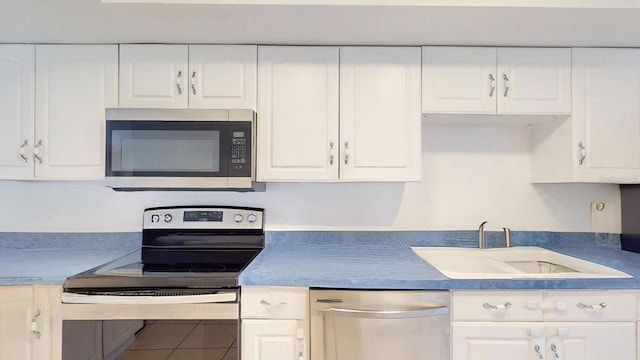 kitchen with sink, tile patterned floors, white cabinets, and stainless steel appliances