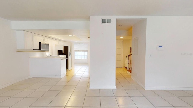 kitchen with kitchen peninsula, white cabinets, and light tile patterned floors