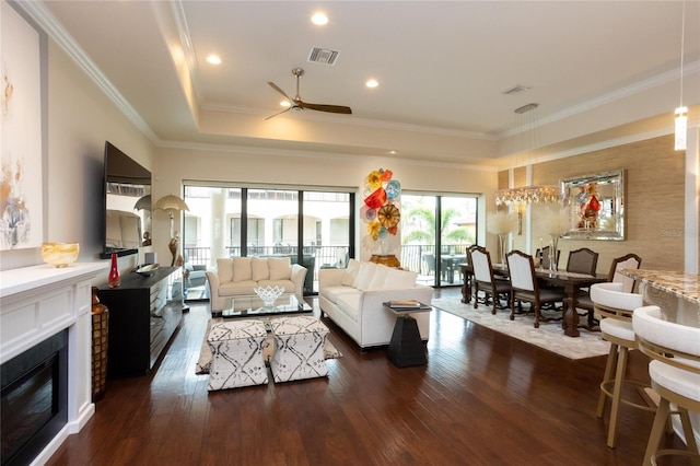living room featuring ceiling fan, ornamental molding, dark hardwood / wood-style floors, and a raised ceiling
