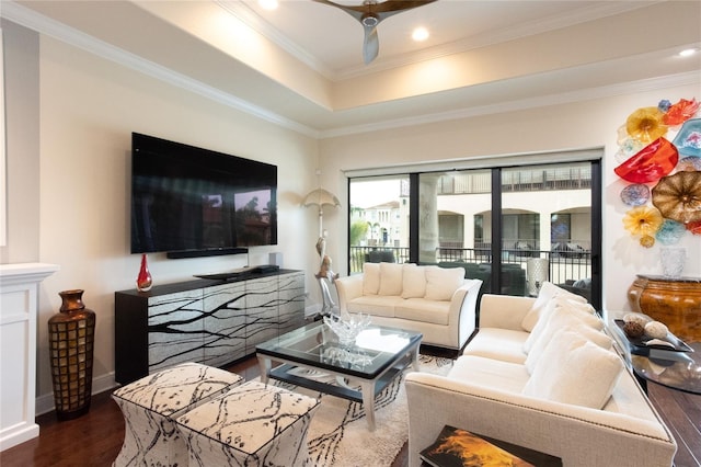 living room with dark hardwood / wood-style flooring, a tray ceiling, ornamental molding, and ceiling fan
