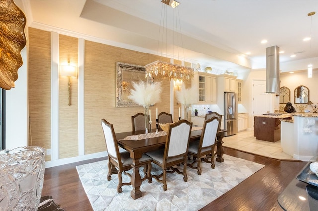 dining space with a tray ceiling, ornamental molding, and light hardwood / wood-style floors