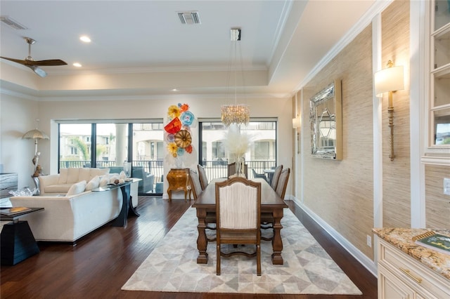 dining area featuring a tray ceiling, ceiling fan with notable chandelier, ornamental molding, and dark hardwood / wood-style floors