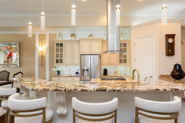 kitchen with cream cabinets, light stone countertops, hanging light fixtures, and appliances with stainless steel finishes