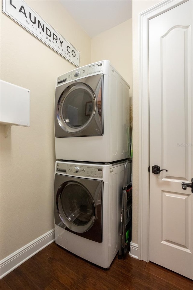 clothes washing area featuring dark wood-type flooring and stacked washing maching and dryer