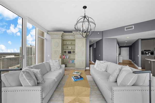 living room with expansive windows, light wood-type flooring, and an inviting chandelier