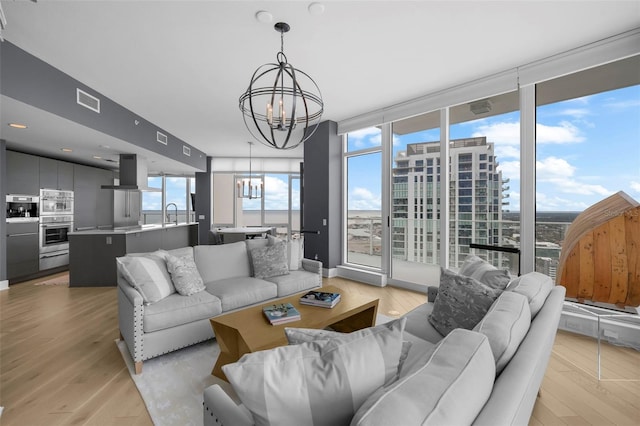 living room featuring light wood-type flooring, a wealth of natural light, and a chandelier