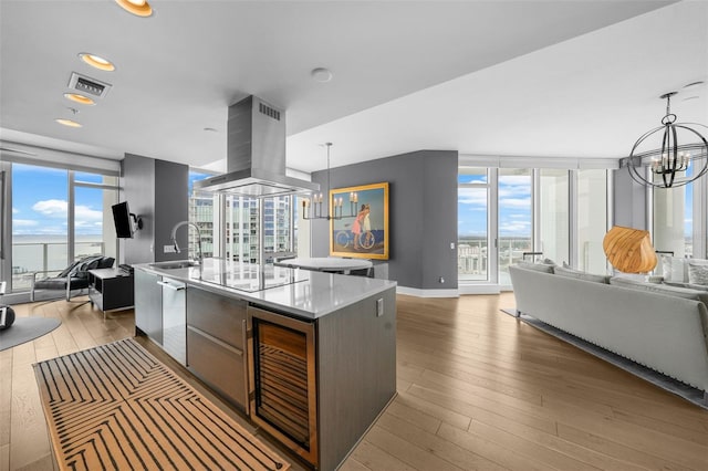 kitchen with decorative light fixtures, an inviting chandelier, island range hood, floor to ceiling windows, and a center island with sink