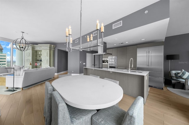 dining space with sink, light hardwood / wood-style floors, and a notable chandelier